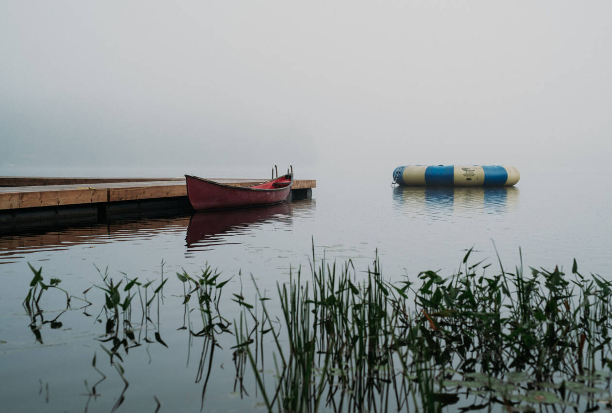 Foggy Lake Waseosa with voyageur canoe and water trampoline pictured in background.